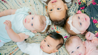 five babies laying face up in a star formation