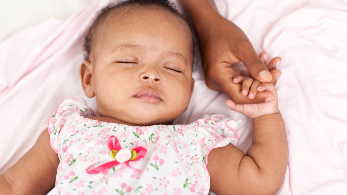 sleeping baby, holding caregiver's hand