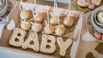 cakepops and cookies shaped as letters spelling 'baby.'